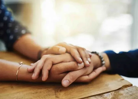 Mains de deux personnes l'une sur l'autre en signe de soutien et de réconfort.